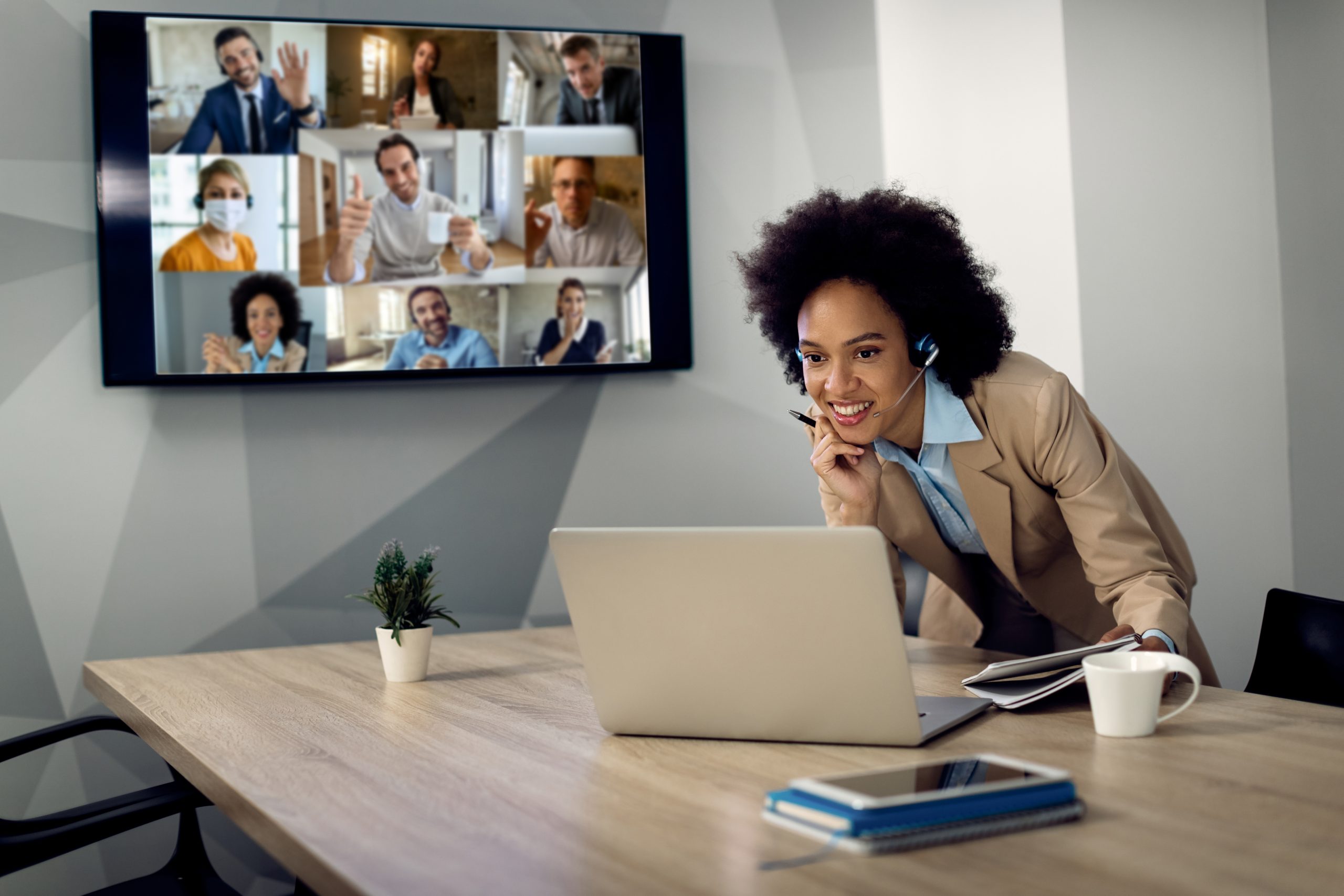 A young woman talks to her colleagues via video chat at her home office.