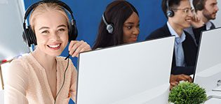 Joyful customer service agents with headphones communicating with clients at call center